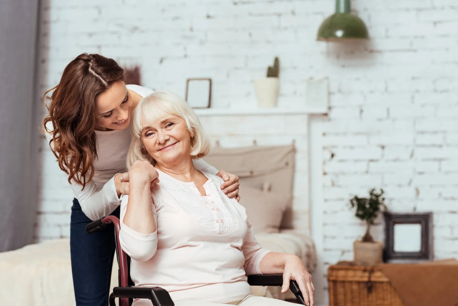 SENIOR GOLD 24 GMBH, Krankenschwester hält die Hand einer fröhlichen älteren Frau, die im Rollstuhl sitzt