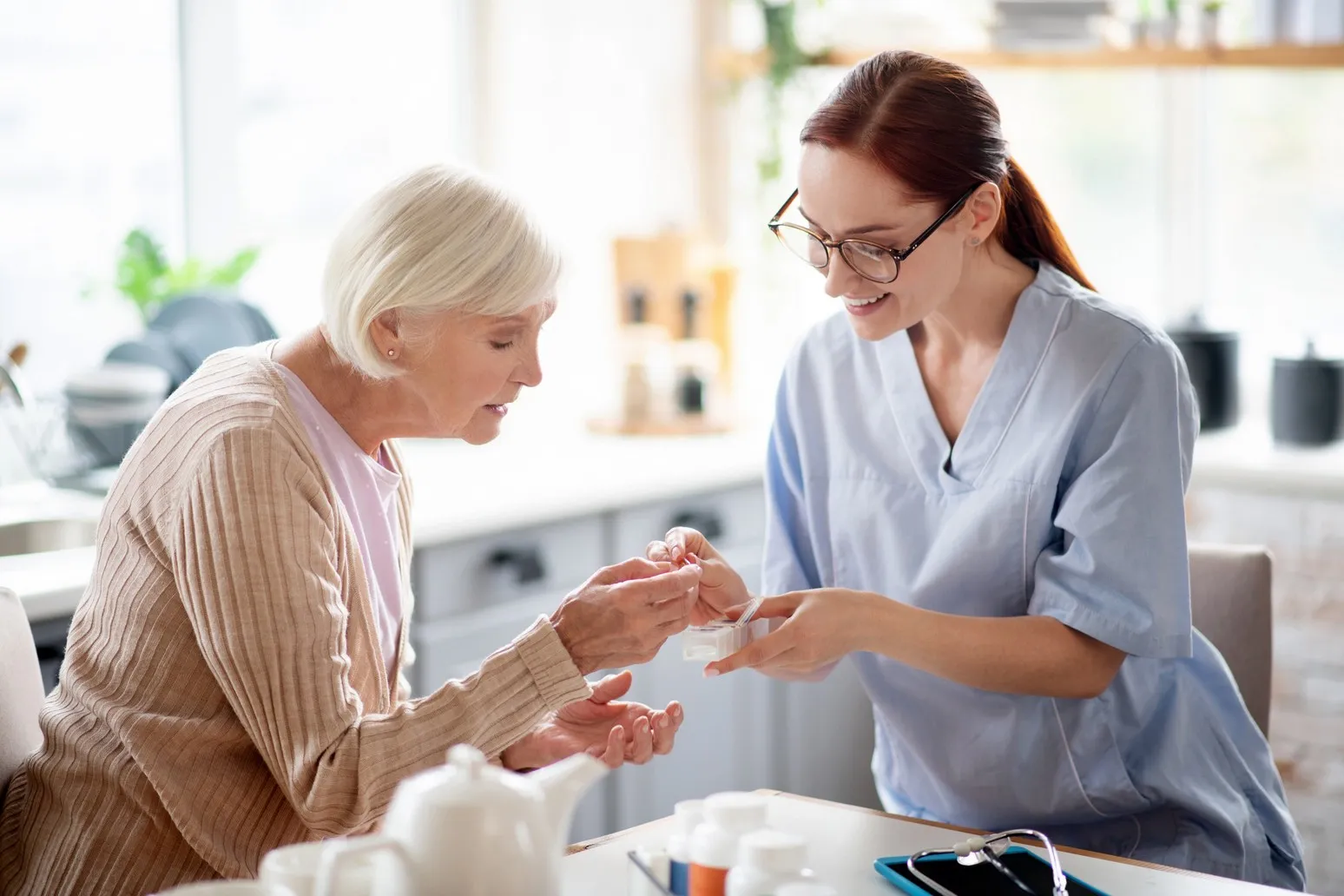 SENIOR GOLD 24 GMBH, Krankenschwester gibt einer alten Dame Vitamine